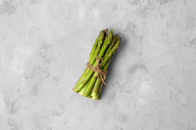 Composizione minima creativa di asparagi verdi freschi sulla tavola di cemento grigia con lo spazio della copia