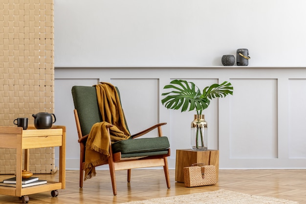 Composizione minimalista all'interno del soggiorno con poltrona di design verde, pannello beige, piante, moquette, scaffale, spazio copia, decorazione ed eleganti accessori personali in un elegante arredamento per la casa.
