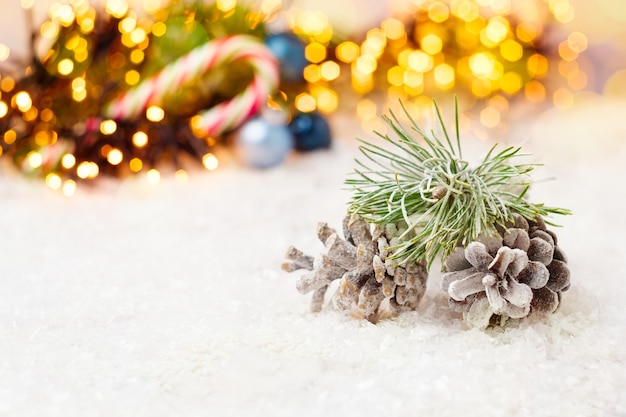 Composizione natalizia con coni nella neve palline blu e ghirlanda con luci