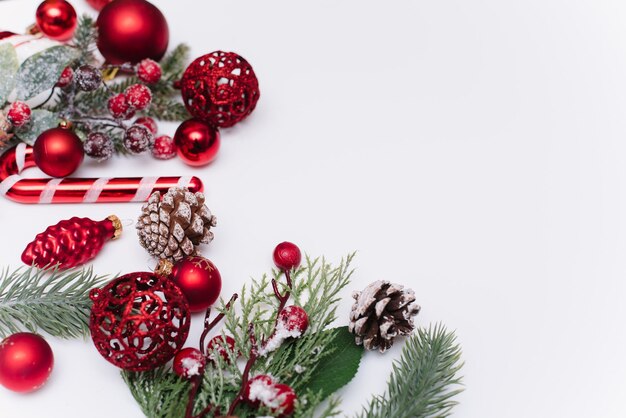 Composizione natalizia con rami di abete decorazioni rosse su sfondo bianco con spazio per la copia