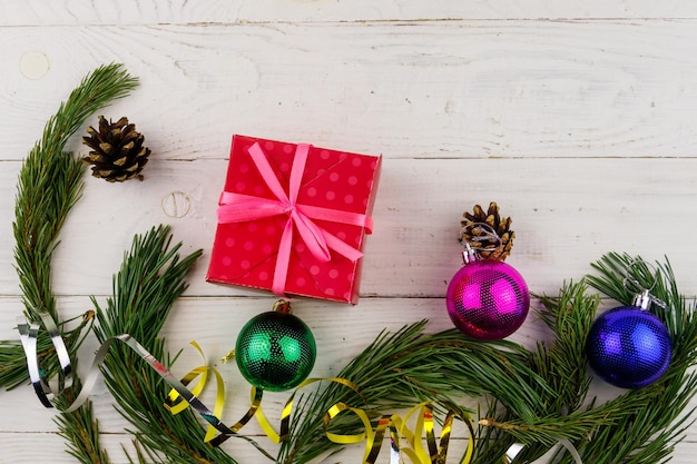 Composizione natalizia con scatola regalo di rami di abete e decorazioni natalizie su tavolo di legno bianco Spazio per la copia vista dall'alto