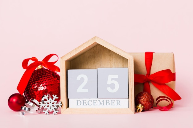 Composizione natalizia del 25 dicembre su sfondo colorato con un calendario in legno con uno spazio per la copia della pallina dei giocattoli della confezione regalo