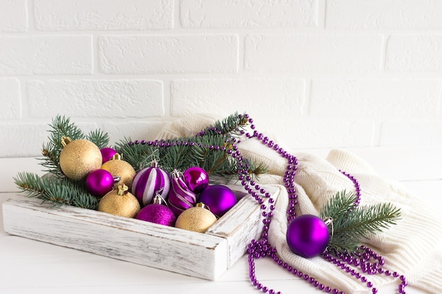 Composizione natalizia di giocattoli luminosi per alberi di Natale e fischi sullo sfondo di un maglione bianco lavorato a maglia. il concetto di un Natale accogliente.