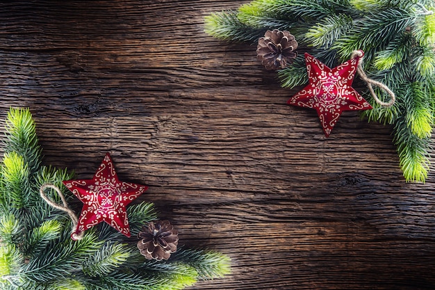 Composizione natalizia rami di abete pigne jingle bells stelle e nastro su tavola in legno rustico