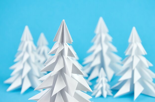 Composizione negli alberi di Natale di origami del Libro Bianco sull'azzurro