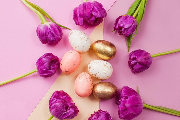 Composizione pasquale con tulipani rosa e uova colorate posizionate su uno sfondo geometrico