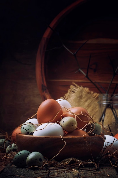 Composizione pasquale con uova colorate di pollo e quaglia in stile rustico sfondo in legno vintage fuoco selettivo