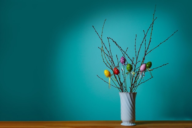 Composizione pasquale Vista frontale di un vaso bianco con ramo decorato con uova di Pasqua