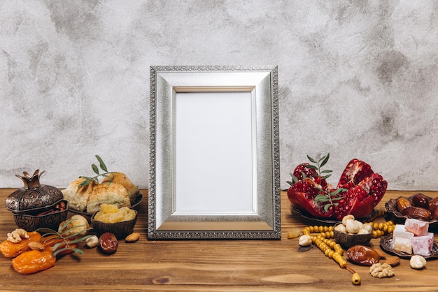 Composizione per il Ramadan Cornice d'argento con copia spazio o mockup vicino alle tradizionali stoviglie islamiche con pasto su tavola di legno