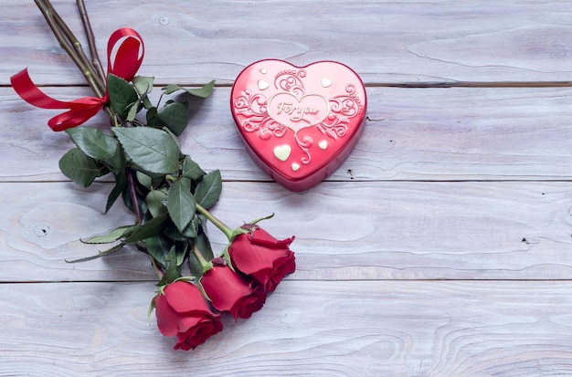 Composizione per San Valentino bouquet di rose e scatola con caramelle a forma su un tavolo