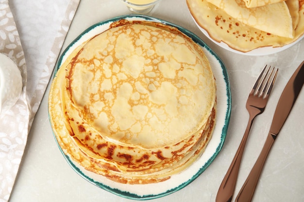 Composizione piatta con pancake sottili freschi su tavolo di marmo grigio chiaro