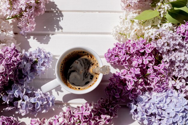 Composizione primaverile piatto bianco tazza di caffè rosa lilla bellissimo bouquet di lillà vecchio libro