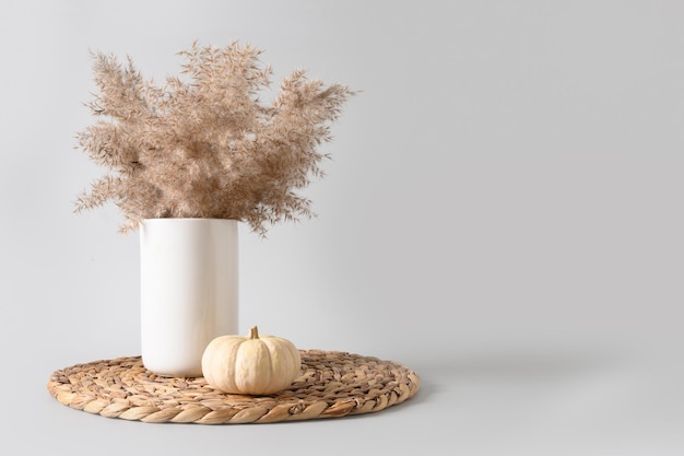 Composizione scandinava minima autunnale con fiori secchi in vaso e zucca bianca Giorno del Ringraziamento