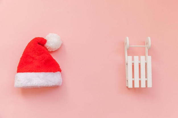 Composizione semplicemente minima Slitta per cappello di Babbo Natale isolata su sfondo rosa pastello colorato alla moda