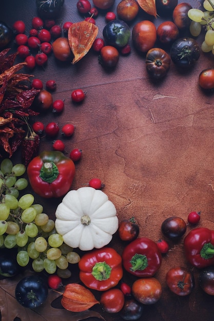 Composizione stagionale con zucche uva foglie autunnali frutta e verdura matura su tavola rustica marrone con spazio per testo halloween o sfondo del ringraziamento