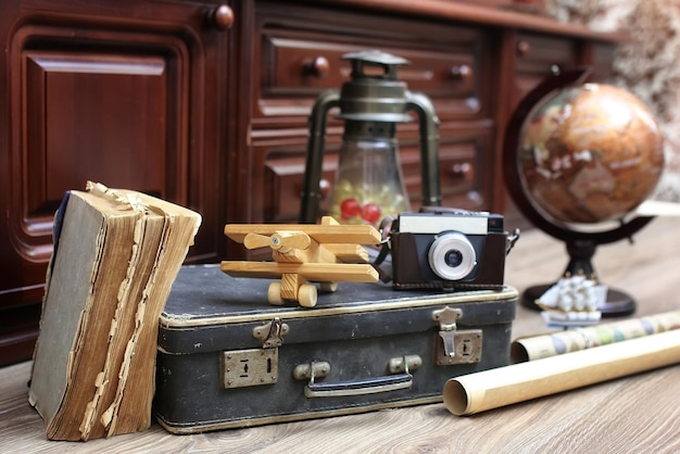 Composizione su pavimento in legno globo vintage con vecchia valigia in pelle con oggetti da viaggio