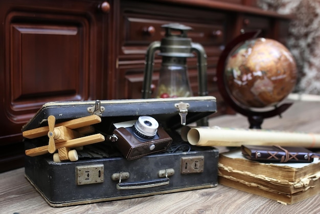 Composizione su pavimento in legno globo vintage con vecchia valigia in pelle con oggetti da viaggio