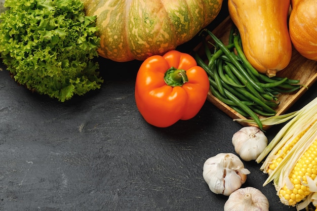 Composizione vegetale autunnale con zucca, mais e pepe su sfondo nero