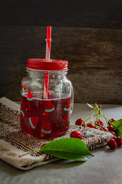 Composta di ciliegie fatta in casa in un bicchiere con una cannuccia sul tavolo con un tovagliolo da cucina e ciliegie
