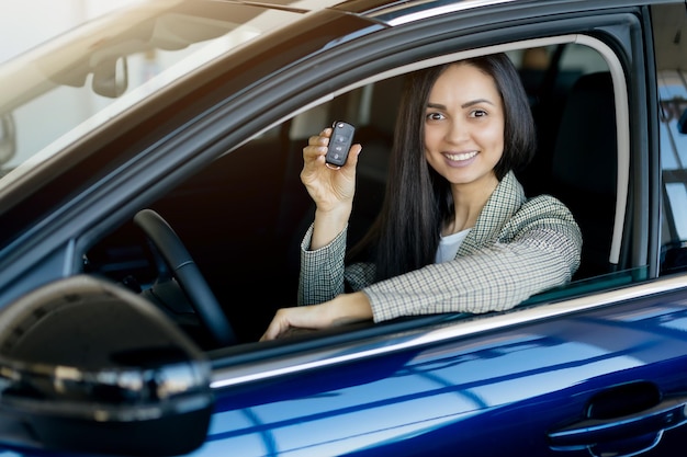 Comprare un'auto nuova donna felice che mostra le chiavi dell'auto fuori dalla finestra