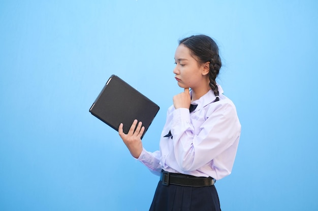 Compressa della tenuta della ragazza della scuola su fondo blu