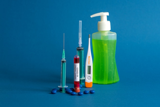 Compressa di medicina, termometro, flacone di disinfettante e siringa o iniezione con una provetta contenente un campione di sangue per testare la presenza di coronavirus