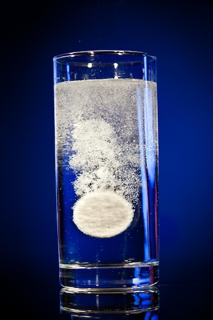 Compressa effervescente in acqua con bolle su sfondo blu