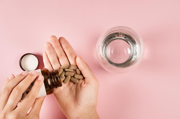Compresse di integratori alimentari in mano per l'assunzione giornaliera di pillole su sfondo rosa Set di pillole di zinco antiossidanti dall'invecchiamento lecitina e adattogeno