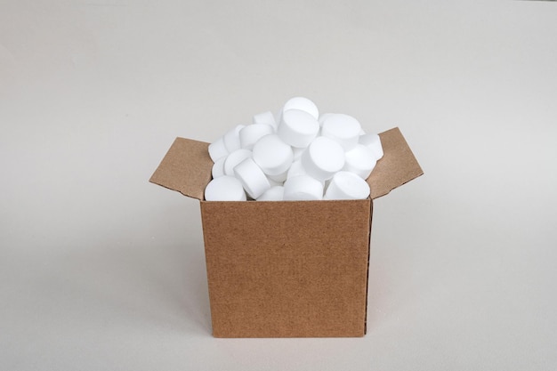 Compresse di sale per lavastoviglie rotonde bianche in una scatola Un set di capsule bianche in una scatola aperta