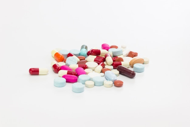 Compresse e capsule multicolori degli antibiotici su fondo bianco.