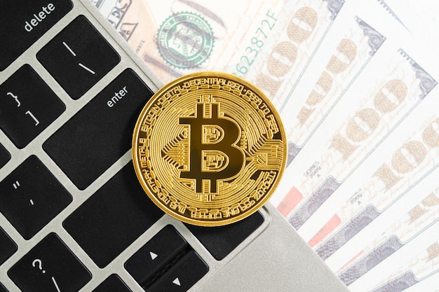 Computer con tastiera per monete Golden Bitcoin e banconote USA Primo piano di monete in metallo lucido bitcoin criptato e dollaro USA