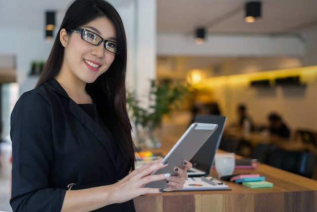 computer della compressa della tenuta del proprietario di affari che sta davanti alla caffetteria con un sorriso