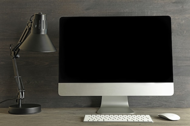 Computer desktop con schermo vuoto su fondo di legno grigio