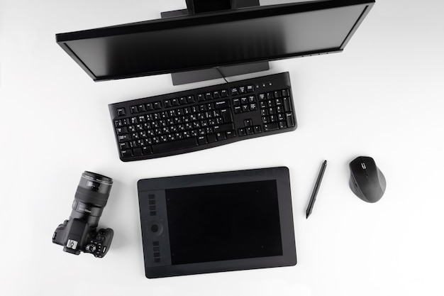 Computer, fotocamera e tablet sulla scrivania. Computer desktop con strumenti di fotoritocco. Moderna area di lavoro creativa per fotografi o designer