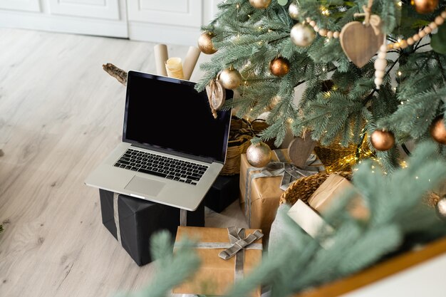 Computer portatile. Albero di Natale e regali sullo sfondo.