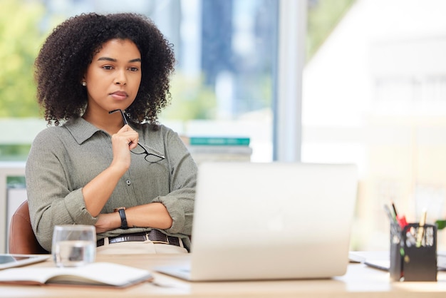 Computer portatile aziendale che pensa e donna nera in ufficio che cerca di risolvere il problema Messa a fuoco dell'idea e impiegata dal Sud Africa con il computer che contempla la soluzione pensierosa o persa nei pensieri da sola