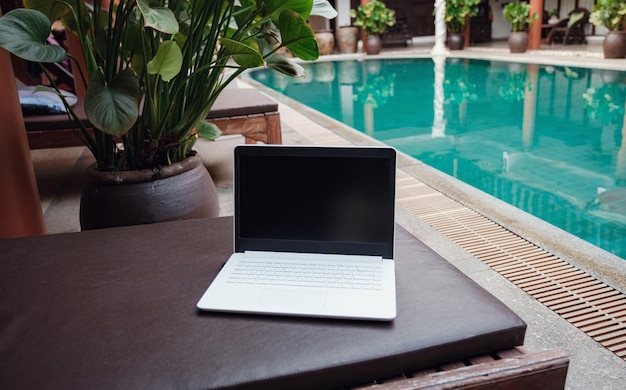 Computer portatile bianco sullo sfondo della piscina in un hotel esotico