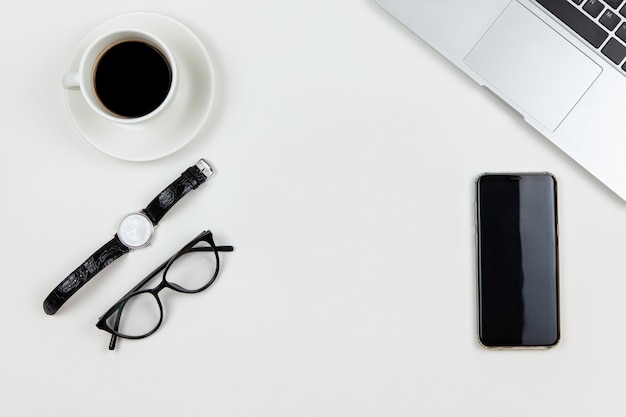 Computer portatile, caffè, orologio da polso, smartphone, occhiali su sfondo bianco