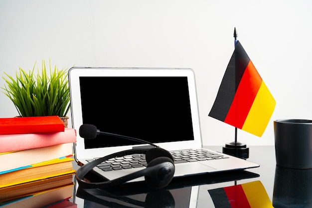 Computer portatile con bandiera tedesca sul concetto educativo del tavolo di lavoro