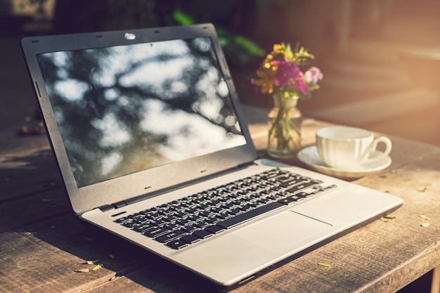 Computer portatile con la tazza di caffè sulla tabella di legno