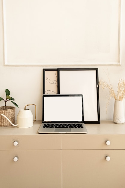 Computer portatile con schermo in bianco pastello beige sul tavolo con decorazioni boho