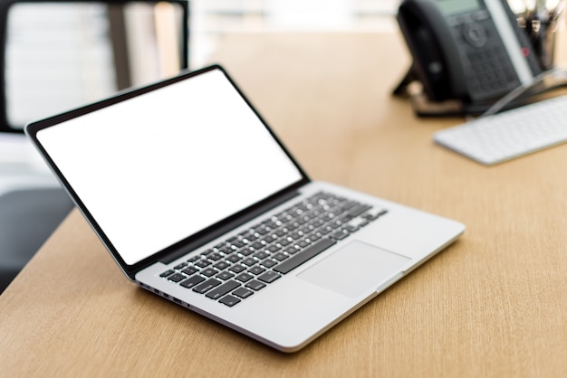 Computer portatile con schermo vuoto sul tavolo di legno e sfondo sfocato