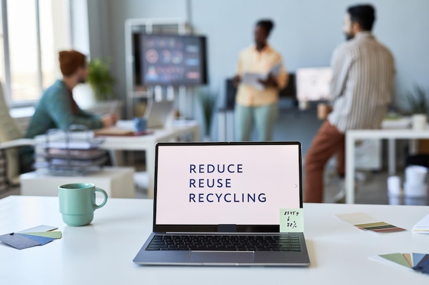 Computer portatile con slogan composto da tre parole su schermo bianco in piedi sul tavolo tra tazza e colore p