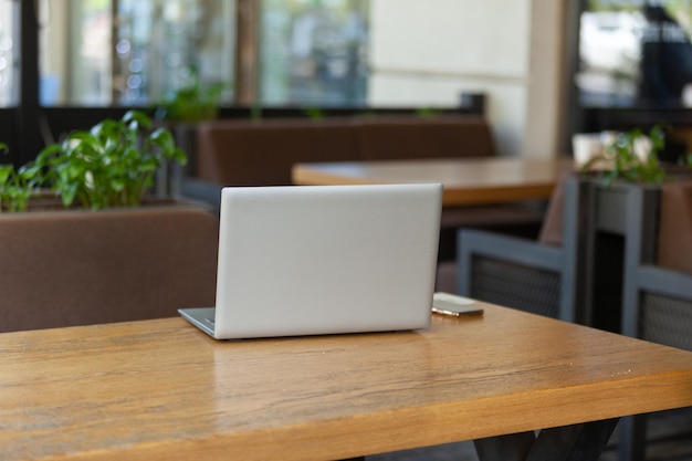 Computer portatile con smartphone sul tavolo del caffè all'aperto