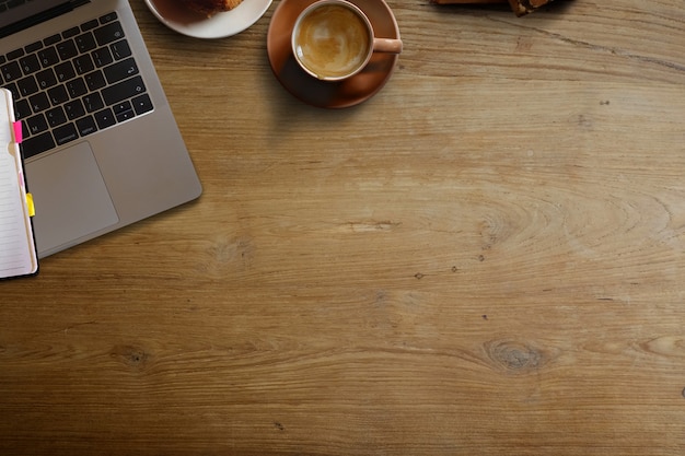 Computer portatile con tazza di caffè marrone e lo spazio della copia sul tavolo scrivania in legno.