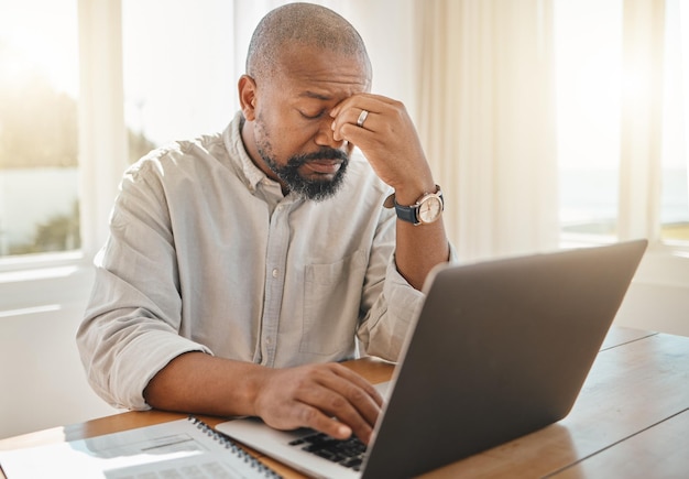 Computer portatile dell'uomo di colore e mal di testa nel lavoro a distanza che soffre di stress da esaurimento o ansia a casa Libero professionista afroamericano stanco dell'uomo d'affari con mal di testa o tensione dal computer sul tavolo