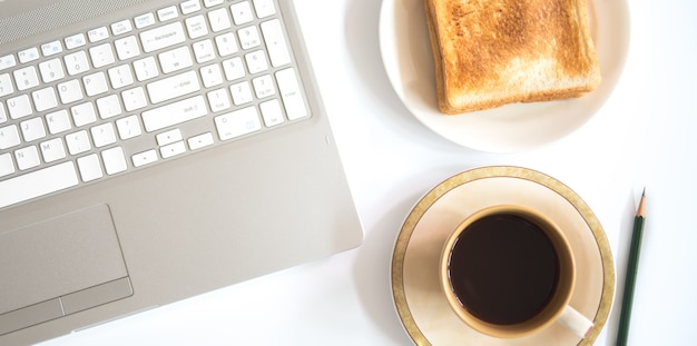 Computer portatile e tazza di caffè con pane tostato, concetto di affari.