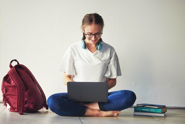 Computer portatile educativo e donna con libri su un pavimento per l'esame di ricerca e la preparazione felice e motivazione Studentessa e progetto di studio di letteratura e libro di assegnazione universitaria online