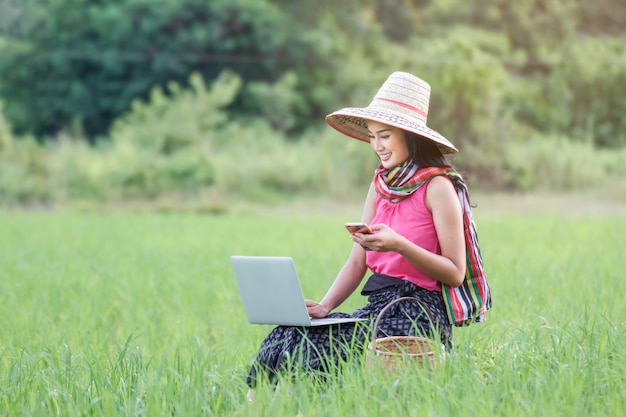 Computer portatile funzionante della bella donna asiatica all&#39;aperto nelle risaie.