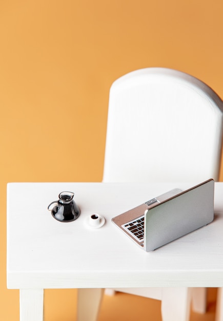 Computer portatile in miniatura e tazza di caffè su un tavolo bianco